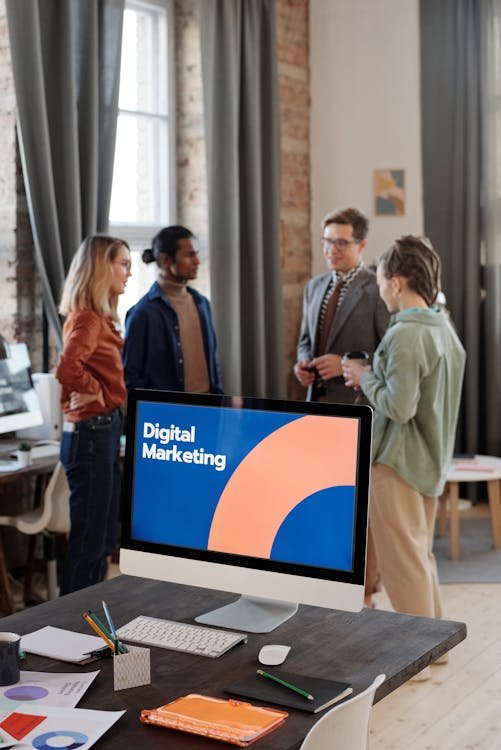Advertising team discussing campaign plans beside a computer showing a digital marketing slide