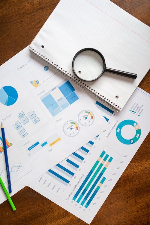 Printed marketing reports with bar charts and a magnifying glass on a desk