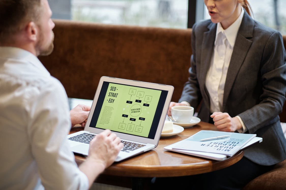 Two people reviewing a strategy plan on a laptop in a cafe meeting