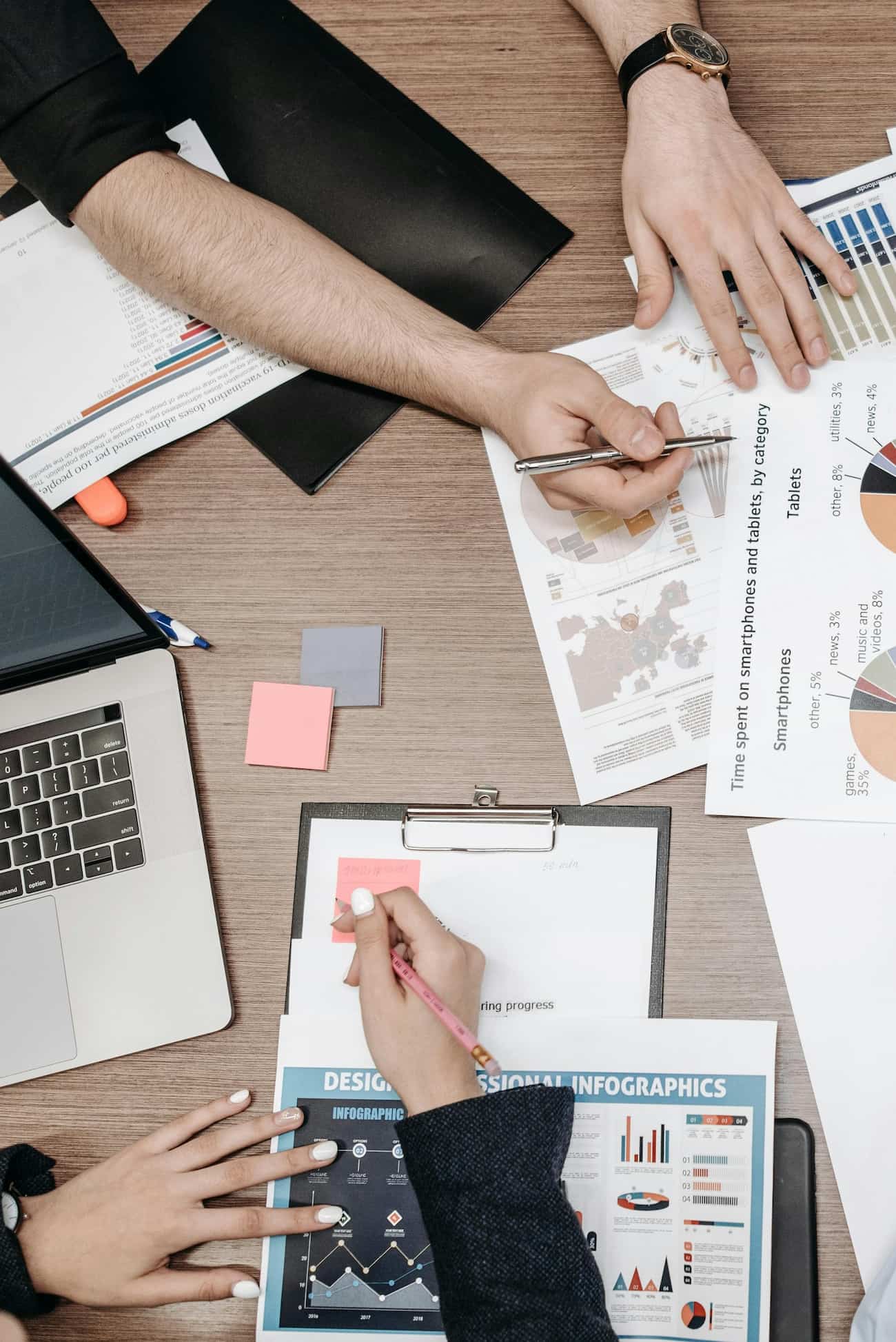 Marketing team reviewing printed reports and charts around a desk while planning a digital marketing strategy