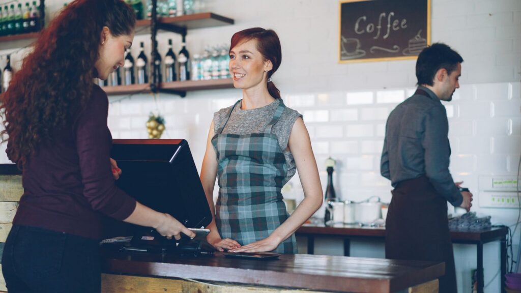 Cafe worker serving a smiling customer at the counter, illustrating customer retention after the festive rush