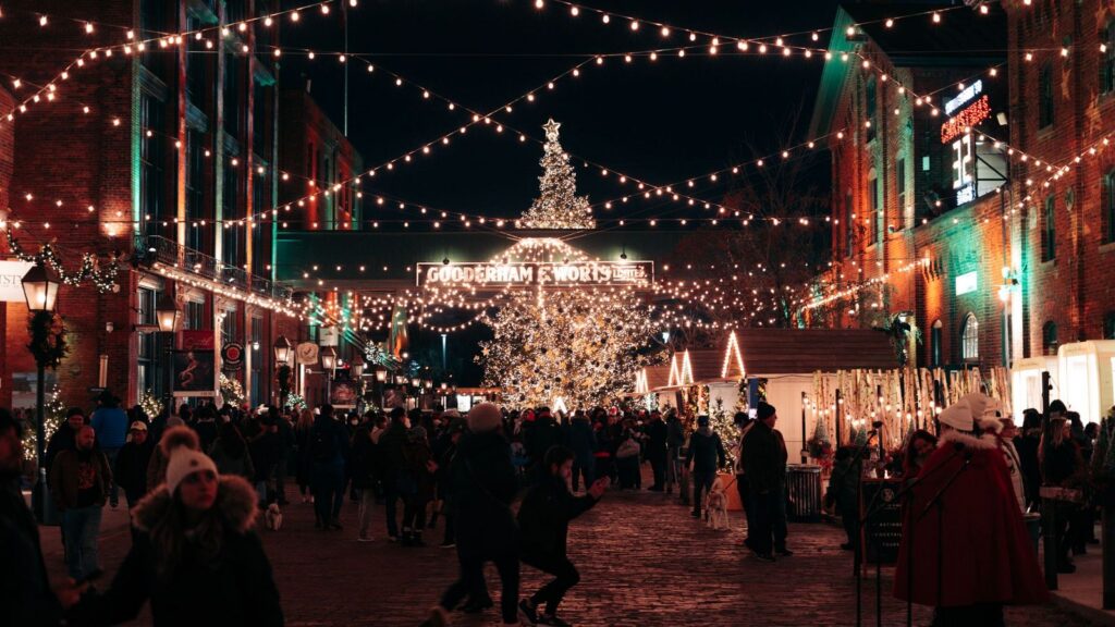 Crowd at a Christmas market with lights and a lit tree, illustrating Christmas spending 2026