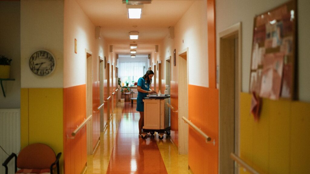 Nurse with a trolley in a hospital corridor, illustrating how government-funded jobs support consumer spending
