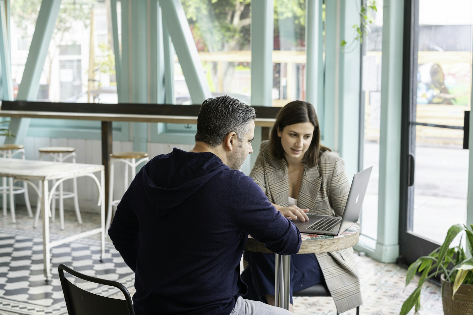Account manager meeting a client at a laptop in a cafe