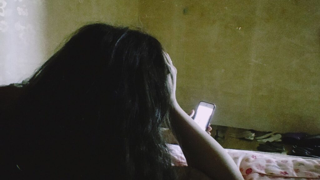 Person lying in bed scrolling on a phone at night, illustrating declining Facebook ads performance